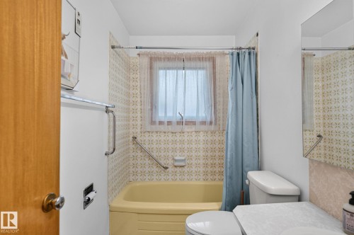 Bathroom featuring a built-in bathtub, tiled surround with patterned accents, and a window with privacy covering - 12908 104 Street Nw, Edmonton, AB - Indoor Photo Showing Bathroom