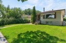 Stucco exterior with a stone-finish foundation, featuring a prominent front bay window with an awning - 12908 104 Street Nw, Edmonton, AB  - Outdoor 