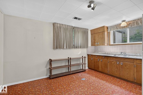 Kitchenette featuring wood-finish cabinetry, a single basin sink, white countertops, and a tiled backsplash - 12908 104 Street Nw, Edmonton, AB - Indoor Photo Showing Kitchen With Double Sink