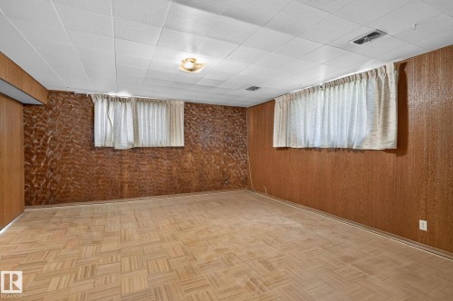 Spacious interior room featuring wood-finish wall paneling, a drop ceiling, and two windows - 12908 104 Street Nw, Edmonton, AB - Indoor Photo Showing Other Room