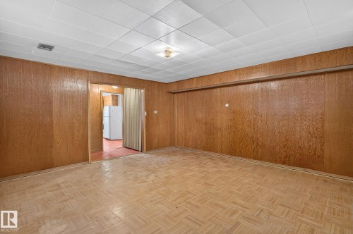 Room featuring wood paneling, drop ceiling, and patterned flooring - 12908 104 Street Nw, Edmonton, AB - Indoor Photo Showing Other Room