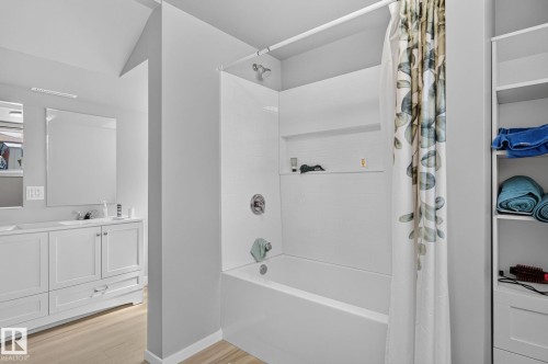 Bathtub with white tile surround and integrated shelving, featuring a chrome shower head and faucet - 12908 104 Street Nw, Edmonton, AB - Indoor Photo Showing Bathroom