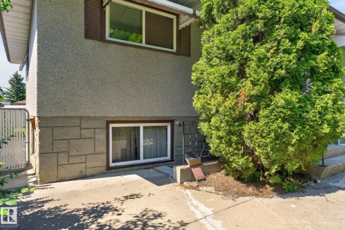 Exterior facade featuring a textured stucco finish, a lower level of stone-patterned siding, and white-framed windows - 12908 104 Street Nw, Edmonton, AB - Outdoor With Exterior