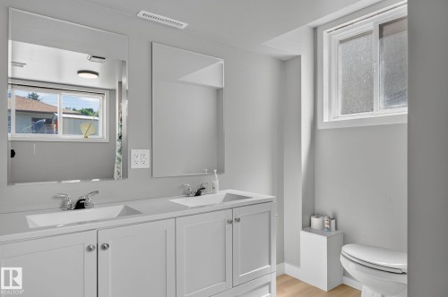 Bathroom featuring a dual-sink vanity with white cabinetry, chrome faucets, and two large mirrors - 12908 104 Street Nw, Edmonton, AB - Indoor Photo Showing Bathroom