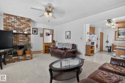 Living area with light-toned carpet flooring and a multi-toned brick fireplace - 