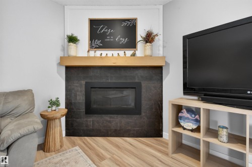 Living area featuring a modern fireplace with a dark tile surround and a natural wood-finish mantel - 18116 81 Avenue, Edmonton, AB 