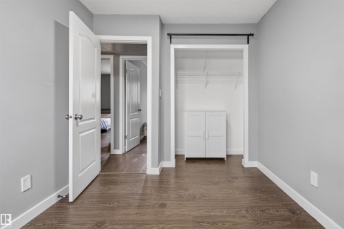 Interior room featuring wood-finish flooring, light gray walls, white trim, and a closet with wire shelving - 18116 81 Avenue, Edmonton, AB 