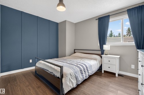Room featuring a paneled accent wall, wood-finish flooring, and a window with white trim - 18116 81 Avenue, Edmonton, AB 