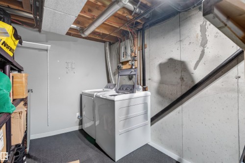 Dedicated utility area featuring a washer and dryer, exposed ceiling joists, and concrete walls - 18116 81 Avenue, Edmonton, AB 