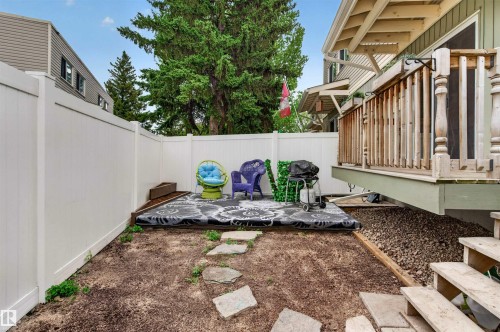 Private fenced yard featuring a raised deck with wood railing, a designated patio area, and flagstone pathway - 18116 81 Avenue, Edmonton, AB 