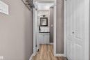 Bathroom entry featuring wood-finish flooring, white subway tile backsplash, a dark vanity mirror, and a two-light wall sconce - 18116 81 Avenue, Edmonton, AB 