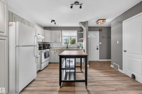 Well-appointed kitchen featuring white cabinetry, light countertops, subway tile backsplash, and wood-finish flooring - 18116 81 Avenue, Edmonton, AB 