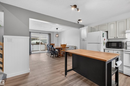 Kitchen featuring a movable island with a wood countertop, white cabinetry, track lighting, and wood-finish flooring - 18116 81 Avenue, Edmonton, AB 