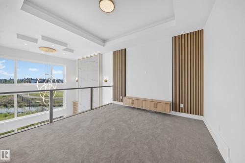 Spacious upper-level area featuring a contemporary glass and metal railing overlooking a lower space - 2808 191 Street Nw, Edmonton, AB - Indoor Photo Showing Other Room