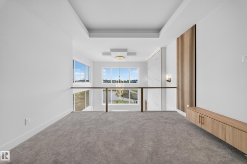 Upper-level landing featuring plush gray carpeting, a contemporary glass and wood-finish railing, and a tray ceiling - 2808 191 Street Nw, Edmonton, AB - Indoor Photo Showing Other Room