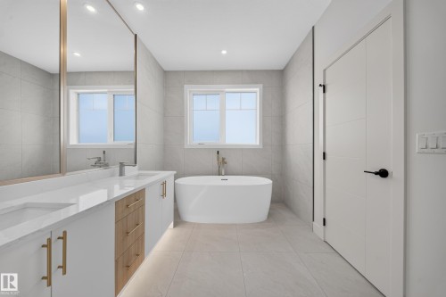 Contemporary bathroom featuring a freestanding tub, dual vanity with undermount sinks, and light-toned tile flooring - 2808 191 Street Nw, Edmonton, AB - Indoor Photo Showing Bathroom