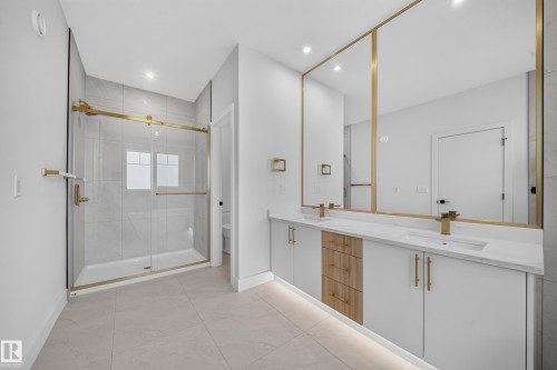 Contemporary bathroom featuring a dual vanity with white cabinetry, wood-finish drawer accents, and a large integrated mirror - 2808 191 Street Nw, Edmonton, AB - Indoor Photo Showing Bathroom