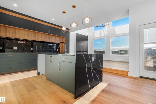 Modern kitchen featuring a black-veined island countertop, light wood-finish flooring, and a two-tone cabinet design with dark lower and light wood-tone upper cabinetry - 2808 191 Street Nw, Edmonton, AB - Indoor Photo Showing Kitchen