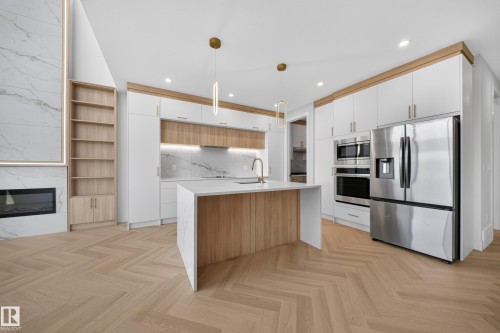 Open-concept kitchen featuring an island with integrated sink, stainless steel appliances, and two-tone cabinetry with gold-toned hardware - 2808 191 Street Nw, Edmonton, AB - Indoor Photo Showing Kitchen