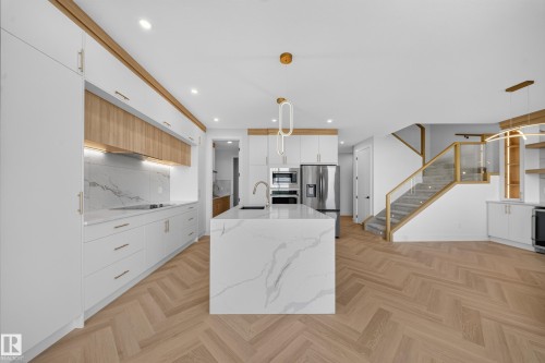 Contemporary kitchen featuring a waterfall island, integrated appliances, and herringbone wood-finish flooring - 2808 191 Street Nw, Edmonton, AB - Indoor Photo Showing Kitchen