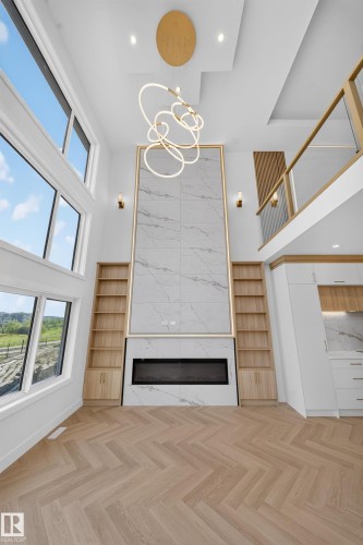 Two-story living area featuring a full-height tiled fireplace surround with a linear electric firebox, integrated shelving with lower cabinetry, and herringbone-pattern wood-finish flooring - 2808 191 Street Nw, Edmonton, AB - Indoor Photo Showing Other Room