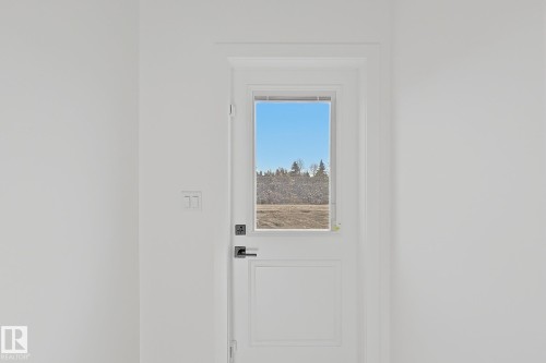 White paneled door featuring a window with integrated blinds, matte black hardware, and crisp white trim - 4215 63 Street, Beaumont, AB - Indoor Photo Showing Other Room
