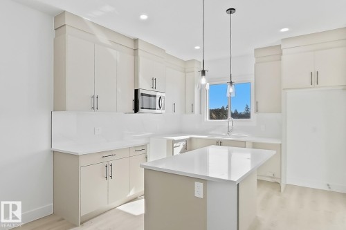 Modern kitchen featuring light cabinetry with contemporary hardware, white countertops, and a coordinating backsplash - 4215 63 Street, Beaumont, AB - Indoor Photo Showing Kitchen With Upgraded Kitchen