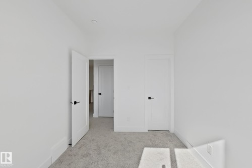 Neutral tone walls featuring white trim, two flat-panel doors with matte black hardware, and light-colored carpeting - 4215 63 Street, Beaumont, AB - Indoor Photo Showing Other Room