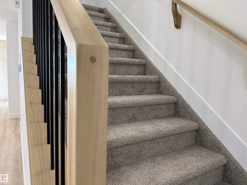 Staircase with light wood-finish handrail and black metal balusters - 4215 63 Street, Beaumont, AB - Indoor Photo Showing Other Room