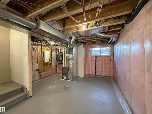 Unfinished basement with a painted concrete floor, exposed wood ceiling joists, and a perimeter insulated with pink fiberglass batting - 4215 63 Street, Beaumont, AB - Indoor Photo Showing Basement