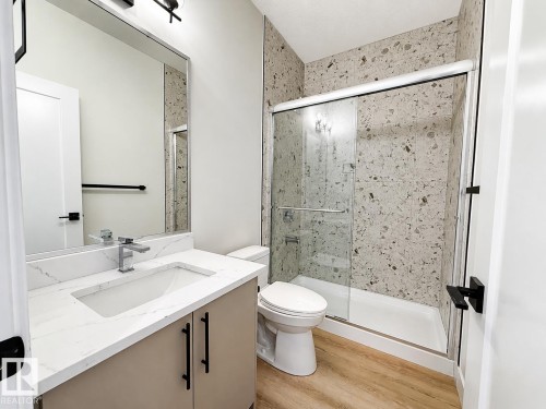 Bathroom featuring a vanity with a white countertop and undermount sink, chrome faucet, and rectangular mirror - 4215 63 Street, Beaumont, AB - Indoor Photo Showing Bathroom