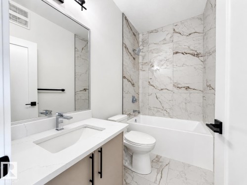 Contemporary bathroom featuring a white vanity with a quartz countertop and integrated sink - 4215 63 Street, Beaumont, AB - Indoor Photo Showing Bathroom