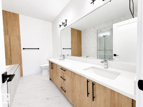 Double vanity featuring wood-finish cabinetry, white countertops, and integrated sinks - 4215 63 Street, Beaumont, AB - Indoor Photo Showing Bathroom