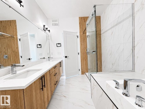 Modern bathroom featuring a double vanity with wood-finish cabinetry, white countertops, and dual undermount sinks - 4215 63 Street, Beaumont, AB - Indoor Photo Showing Bathroom