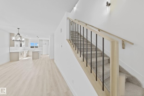 Carpeted staircase with light wood-finish handrail and black metal balusters - 4215 63 Street, Beaumont, AB - Indoor Photo Showing Other Room