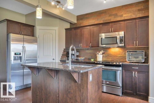 With Stainless Steel appliances, granite counter tops, corner pantry and island - #10 15151 43 St Nw, Edmonton, AB - Indoor Photo Showing Kitchen With Upgraded Kitchen