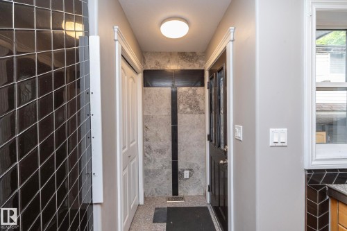 Hallway featuring grey wall paint, black diamond-patterned wall tiles, and a white bi-fold closet door - 11915 77 Street Nw, Edmonton, AB - Indoor Photo Showing Other Room