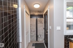 Hallway featuring grey wall paint, black diamond-patterned wall tiles, and a white bi-fold closet door - 