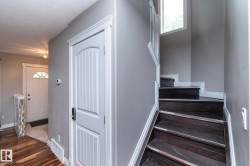 Dark wood-finish staircase with white trim, featuring a window and a white paneled door with contemporary hardware - 
