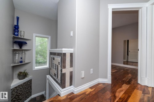 Upper-level landing featuring wood-finish flooring, a tiled half-wall, and a corner window - 11915 77 Street Nw, Edmonton, AB - Indoor Photo Showing Other Room