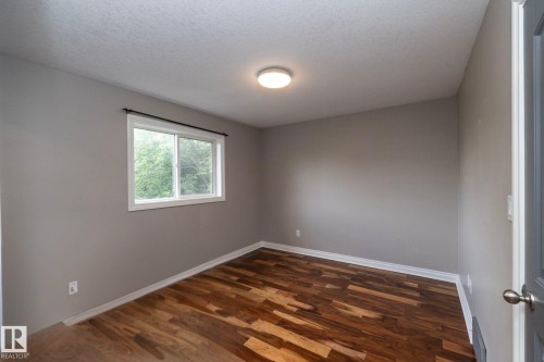 Room with wood-finish flooring, neutral gray walls, and white trim - 11915 77 Street Nw, Edmonton, AB - Indoor Photo Showing Other Room