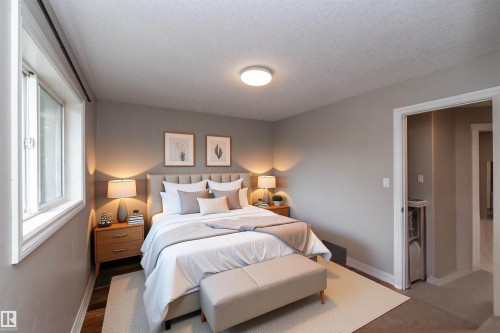 Spacious room featuring neutral paint tones, a large window, a ceiling-mounted light fixture, and wood-finish flooring - 11915 77 Street Nw, Edmonton, AB - Indoor Photo Showing Bedroom