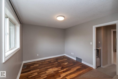 Room with wood-finish flooring, neutral wall tones, white baseboards, and a flush-mount ceiling light fixture - 11915 77 Street Nw, Edmonton, AB - Indoor Photo Showing Other Room