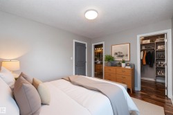 Bedroom featuring light gray wall paint, a built-in closet with custom shelving and wood-finish flooring, a dark gray paneled door, and a flush mount ceiling light - 
