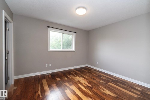 Room featuring wood-finish flooring, a window with a black curtain rod, light gray wall paint, white baseboards, and a ceiling-mounted light fixture - 11915 77 Street Nw, Edmonton, AB - Indoor Photo Showing Other Room