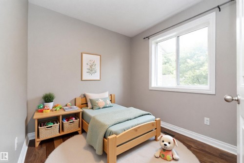 Light-filled room featuring a large window, neutral wall paint, rich wood-finish flooring, and white trim - 11915 77 Street Nw, Edmonton, AB - Indoor Photo Showing Bedroom