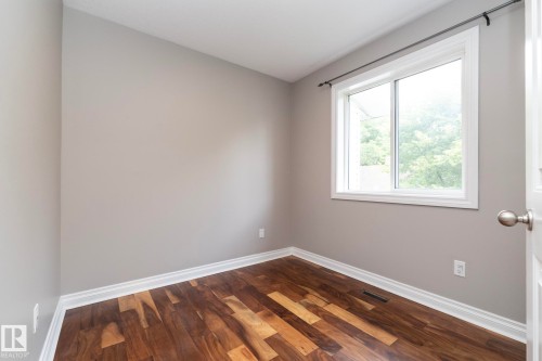 Room featuring neutral wall paint, wood-finish flooring, white baseboards, and a window with white trim - 11915 77 Street Nw, Edmonton, AB - Indoor Photo Showing Other Room