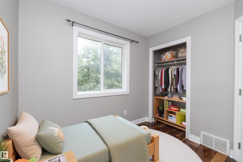Room featuring neutral wall tones, a double window with white trim, and a built-in closet with shelving and hanging storage - 11915 77 Street Nw, Edmonton, AB - Indoor Photo Showing Bedroom