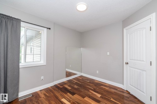 Room featuring wood-finish flooring, a white paneled door, and a bright window - 11915 77 Street Nw, Edmonton, AB - Indoor Photo Showing Other Room