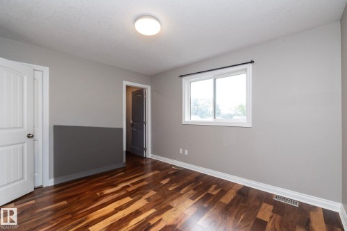 Neutral-toned room with wood-finish flooring, a white trim window, and white baseboards - 11915 77 Street Nw, Edmonton, AB - Indoor Photo Showing Other Room